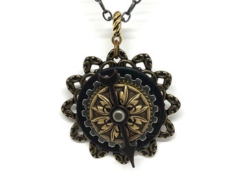 May include: A silver chain necklace with a black and gold steampunk-style pendant featuring a gear, a wrench, and a floral design.