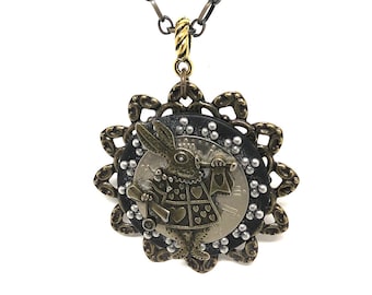 May include: A silver and gold necklace with a round pendant featuring a white rabbit holding a pocket watch and a banner that says "I'm Late". The pendant is surrounded by a decorative, scalloped border.