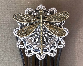 May include: A brown tortoiseshell hair comb with a decorative dragonfly design. The dragonfly is made of silver and gold metal and has intricate details.