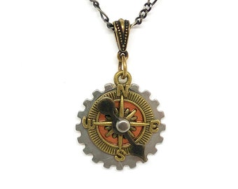 May include: A silver and brass compass pendant necklace with a gear design. The compass face has a red and orange background with black markings. The necklace has a silver chain.
