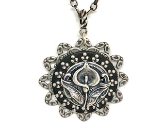 May include: A silver necklace with a black and silver pendant featuring a stylized flower design.