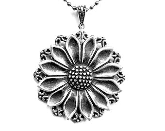 May include: A silver necklace with a large, detailed sunflower pendant. The chain is a simple ball chain.