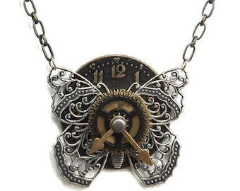 May include: A silver and gold necklace with a clock face and butterfly wings. The clock face has Roman numerals and a gear design. The butterfly wings are intricate and detailed.