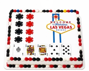 May include: A rectangular sheet cake with white frosting, decorated with a Las Vegas sign, red and black poker chips, and five playing cards including an Ace, Queen, King, 5, and 8 of spades. The border features alternating red, black, and white frosting.