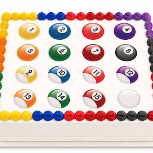 May include: A rectangular cake decorated with colorful frosting and billiard ball images. The cake features a white base with a border of rainbow-colored frosting. Sixteen billiard balls, numbered 1 through 15, are arranged on top.
