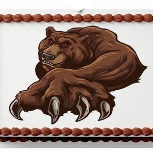 May include: A rectangular cake with a brown border and a white top. The cake features a brown illustration of a bear with red eyes and large claws. The bear is in a dynamic pose, with its paw extended.