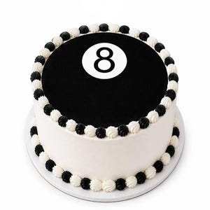 May include: A round cake with smooth white frosting on the sides and a black circular top featuring a large white circle with the number 8 in the center. The top and bottom edges are decorated with alternating black and white piped frosting dollops.