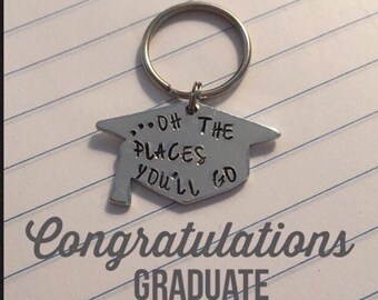May include: Silver graduation cap keychain with the text "...Oh The Places You'll Go" and the words "Congratulations Graduate" on a lined notebook background.