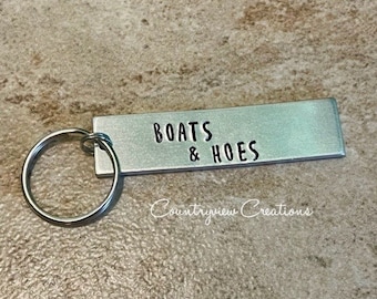 May include: Silver keychain with a rectangular tag that reads "BOATS & HOES".