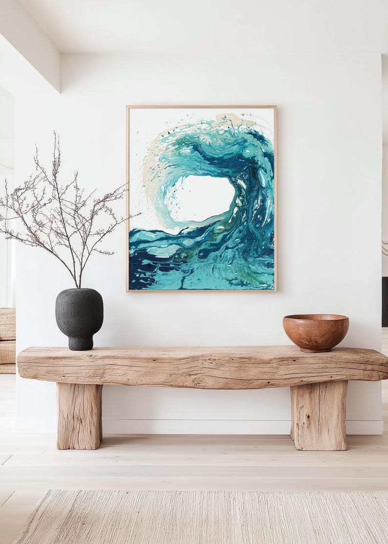 May include: A framed wall art print featuring an abstract painting of a crashing ocean wave in shades of teal, turquoise, and deep blue against a white background, displayed in a light wood frame hanging on a plain white wall.