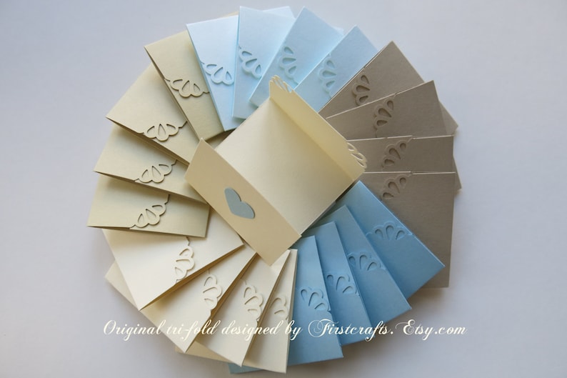 May include: A set of 15 tri-fold cards in beige, light blue, and gray. The cards have a decorative scalloped edge and a heart-shaped cutout. The text "Original tri-fold designed by Firstcrafts. Etsy.com" is printed at the bottom of the image.