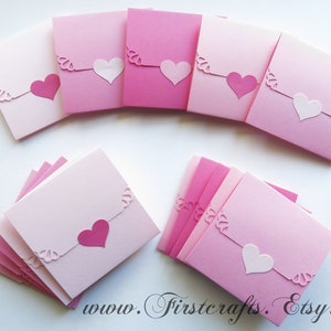 May include: A stack of pink and white folded cards with a heart cut-out on each card. The cards are decorated with a delicate lace pattern. The text "www.Firstcrafts.Etsy.com" is visible at the bottom of the image.