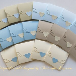 May include: A set of 18 tri-fold favor boxes in three colors: cream, light blue, and beige. Each box features a cut-out design of a heart with a scalloped edge. The boxes are perfect for holding small gifts or favors.