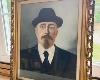 May include: An antique portrait of a man in a black hat, glasses, and suit, framed in an ornate gold frame. The portrait is a vintage piece, likely from the early 20th century, and is a classic example of portraiture.