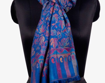 May include: A blue pashmina shawl with a floral pattern in shades of pink, purple, and orange. The shawl has a fringed edge and is draped over a black mannequin.