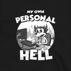 Op de afbeelding: Zwart T-shirt met een witte afbeelding van een cartoon-duivel die aan een computer werkt met de tekst "My Own Personal Hell".