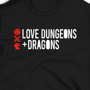May include: Black t-shirt with white text that reads "LOVE DUNGEONS + DRAGONS". The text is accompanied by three red icons: a 20-sided die, a sword and shield, and a dragon.