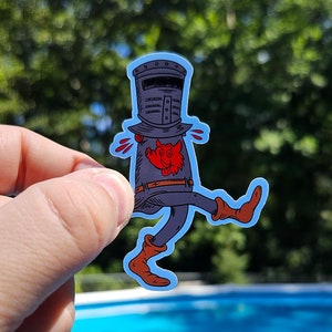 Può includere: Un adesivo con un'illustrazione a cartoni animati di un cavaliere in armatura grigio scuro con un emblema rosso, stivali marroni e un contorno blu. Il cavaliere è in posa da camminata. Il sito web www.paulsimic.com è in basso.