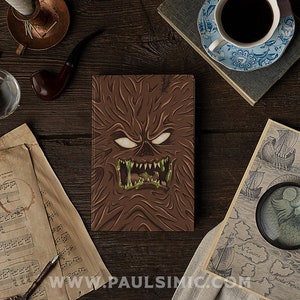 May include: A brown leather-bound journal with a green and brown monster face on the cover. The monster has sharp teeth and glowing eyes.