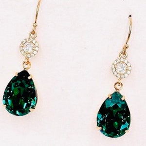 Puede incluir: Un par de pendientes de oro con una piedra verde esmeralda en forma de lágrima y una piedra redonda transparente más pequeña rodeada de piedras transparentes más pequeñas.