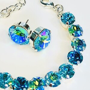 Puede incluir: Un conjunto de pendientes y pulsera de cristal iridiscente azul y verde. La pulsera est&aacute; hecha de cadena de plata y tiene un cierre de langosta.