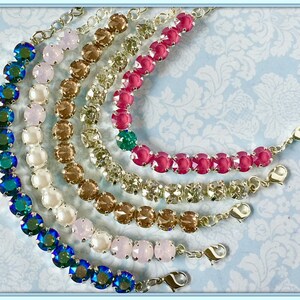 May include: A set of six bracelets with different colored crystal beads. The bracelets are made with silver chain and have a lobster clasp closure. The colors of the beads are teal, pink, white, brown, light brown, and clear.