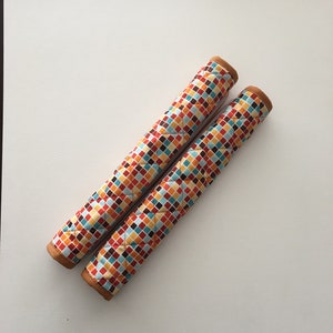 May include: Two brown and beige quilted pot holders with a geometric pattern of red, orange, yellow, blue, and brown squares.