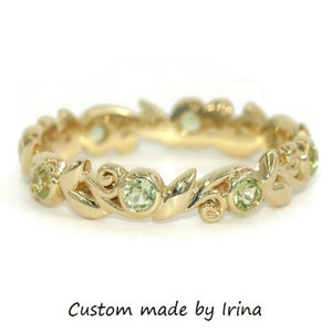 May include: A gold band ring with a delicate leafy design and green gemstones. The ring is custom made by Irina.