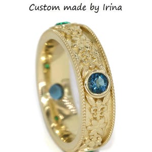 May include: A gold band ring with a detailed floral design and blue and green gemstones. The ring is custom made by Irina.