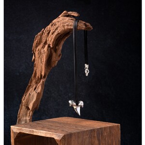 Lifestyle image of poured silver shark's tooth pendant, black deerskin leather necklace and sterling silver findings.