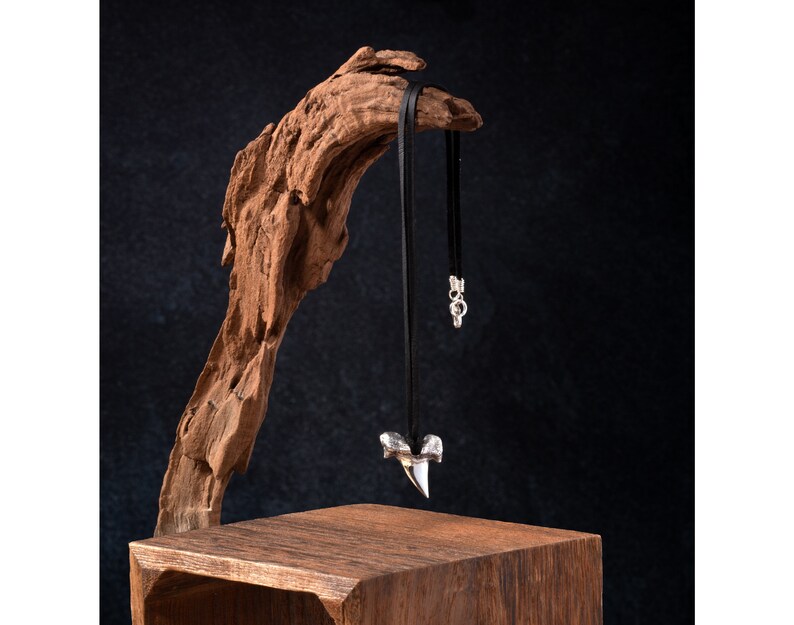 Lifestyle image of poured silver shark's tooth pendant, black deerskin leather necklace and sterling silver findings.