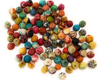 May include: A collection of colorful fabric covered beads. The beads are round and have a variety of patterns and colors, including red, blue, green, yellow, and orange.