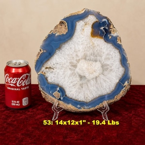 May include: A large blue and white agate geode slice with a crystalline center, displayed on a clear plastic stand next to a red 12 fluid ounce Coca-Cola can. Text on the image reads: 53: 14x12x1" - 19.4 Lbs.