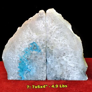 May include: Two natural agate bookends. Each bookend is a light gray color with a blue and white pattern. The bookends are 7 inches tall, 6 inches wide, and 4 inches deep, and weigh 4.9 pounds. A pair of dice are in the lower right corner.