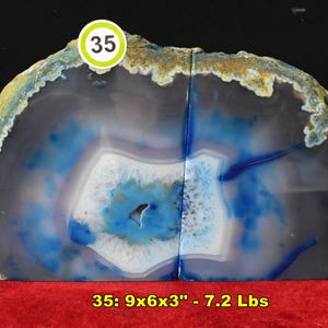 May include: A pair of agate bookends with a striking blue and white pattern. The natural stone has a rough, textured exterior with a smooth, polished interior. The bookends measure 9x6x3 inches and are 7.2 pounds.