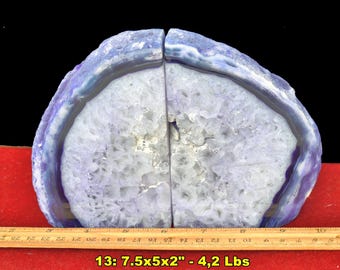 May include: A pair of purple agate bookends featuring a crystalline center and banded edges. A wooden ruler placed in front shows the dimensions are 7.5 inches by 5 inches by 2 inches, with a total weight of 4.2 pounds as indicated by the text.