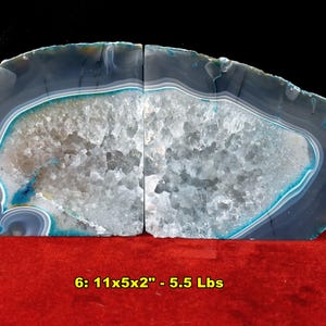 May include: Two agate bookends with a polished, layered appearance. The bookends are primarily gray and white, with bands of blue and turquoise. The text on the image reads "6: 11x5x2" - 5.5 Lbs". A red die is on the right.