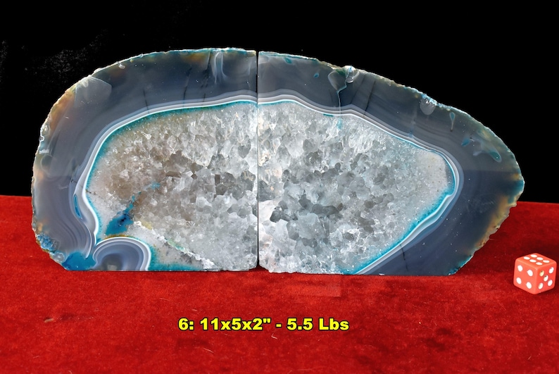 May include: Two agate bookends with a polished, layered appearance. The bookends are primarily gray and white, with bands of blue and turquoise. The text on the image reads "6: 11x5x2" - 5.5 Lbs". A red die is on the right.