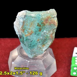 May include: A rough-cut malachite stone, displaying a vibrant green hue with brown and white accents. The stone is approximately 2.5 x 2 x 1.5 inches and weighs 126 grams. The word "Malachite" is printed on the image.