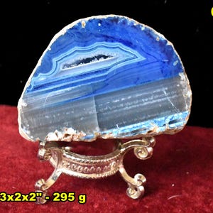 May include: A polished agate stone slice, predominantly blue with white and gray bands, displayed on a decorative gold-colored stand. The stone measures 3x2x2 inches and weighs 295 grams. The number 6 is in the upper right corner.