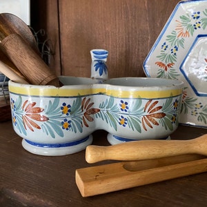 Puede incluir: Un plato de servir de cerámica blanca con un diseño floral azul y amarillo. El plato está dividido en dos secciones y tiene un borde elevado. El plato está sobre una superficie de madera.