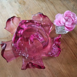 Op de afbeelding: Een roze glazen vaas met een gerimpeld, bloemvormig ontwerp. De vaas is leeg en heeft een heldere, transparante uitstraling.