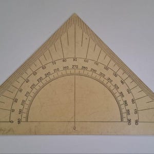 May include: A beige triangular drafting tool featuring a built-in semicircular protractor with degree markings from 0 to 360. The tool includes a vertical center line, a horizontal base line, and the printed text 1960r. in the bottom right corner.