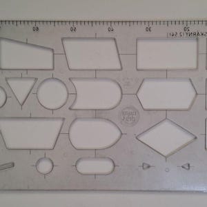 Może przedstawiać: Przezroczysty plastikowy szablon do tworzenia schematów blokowych z różnymi geometrycznymi wycięciami, w tym kwadratami, prostokątami, kołami, trójkątami i rombami. Górna krawędź zawiera linijkę 25 cm, a tekst "ROZTEC ZNAKU TISKARNY 12 551" jest nadrukowany w prawym górnym rogu.