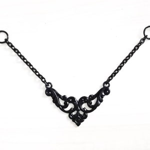 May include: A black necklace with a delicate, ornate pendant. The pendant is made of metal and features a swirling, floral design.
