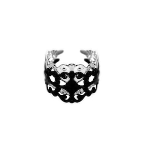 May include: A black metal ring with a delicate, intricate design. The ring is made of a thin metal and has a delicate, openwork design.