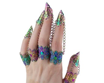 May include: Iridescent finger armor set. The set features ornate, filigree-style designs in shades of purple, green, and gold. Each piece is connected by a delicate chain, creating a unique and eye-catching accessory.