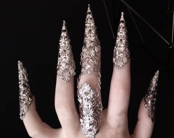 May include: A hand model wearing six silver claw rings with intricate floral designs. The rings are worn on each finger, with the largest ring on the middle finger.