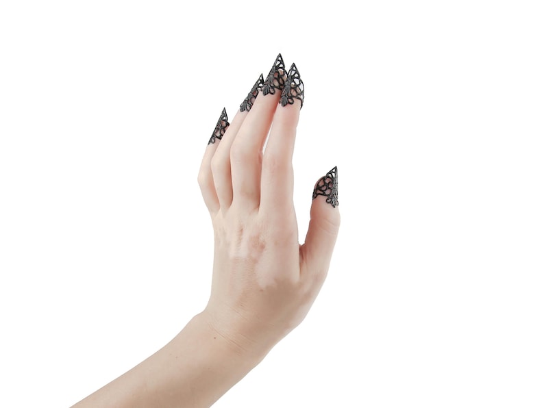 Puede incluir: Una mano con anillos de encaje negro en la punta de los dedos. Los anillos est&aacute;n dise&ntilde;ados para parecer garras.