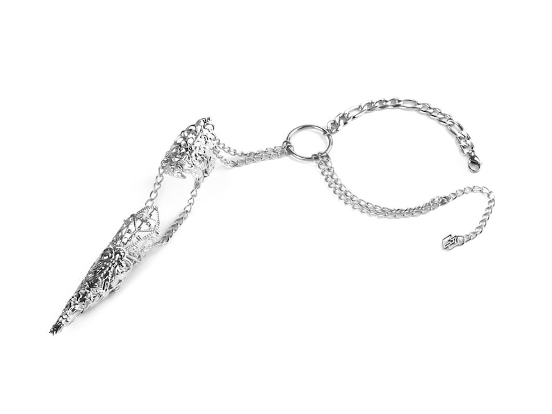 Pu&ograve; includere: Un anello in filigrana argentata con una lunga protezione per le dita a punta collegata a un braccialetto a catena. Il braccialetto ha una chiusura circolare e due maglie a catena.
